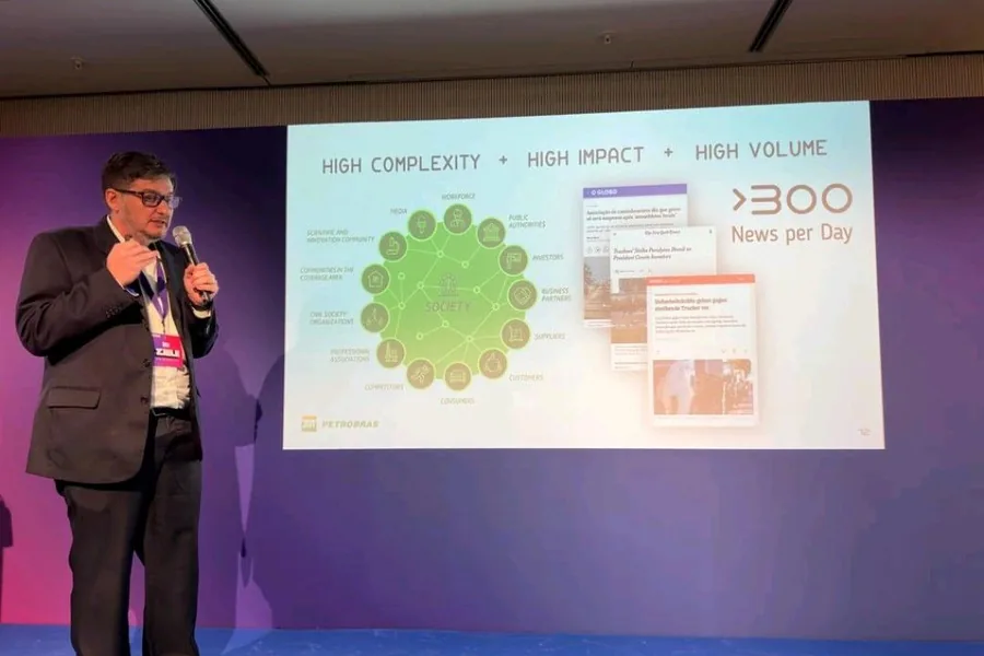Aislan Greca palestrando em Berlim, com um slide sobre alta complexidade, impacto e volume de informação