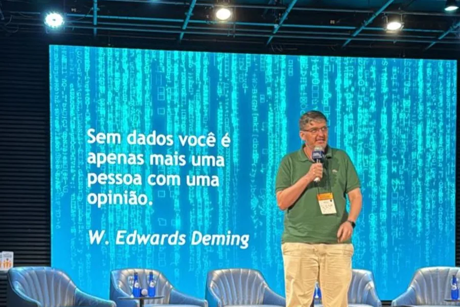 Aislan Greca no palco, com a frase de Deming no telão: sem dados você é apenas mais uma pessoa com uma opinião