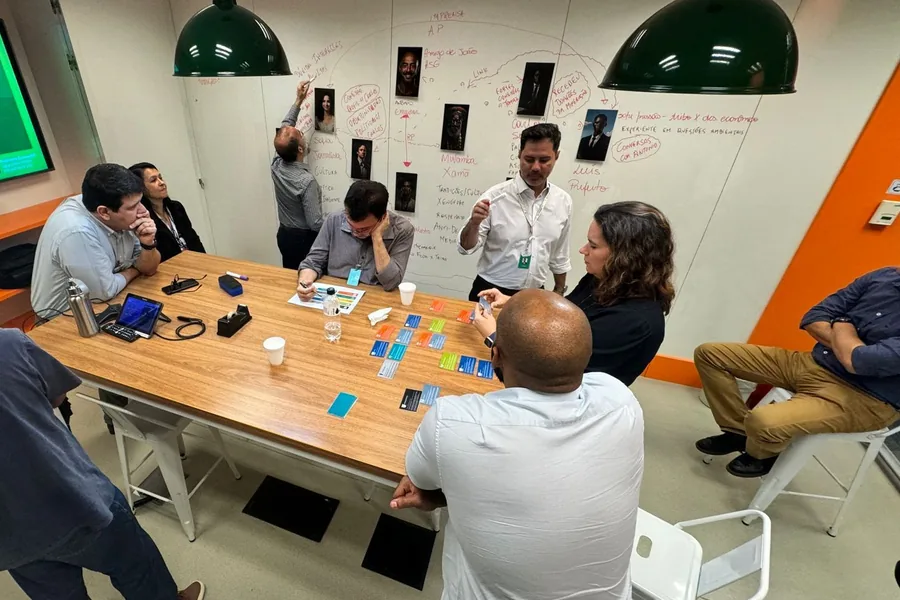 Equipe construindo um mapa de conexões entre pessoas numa parede, com fotos e linhas
